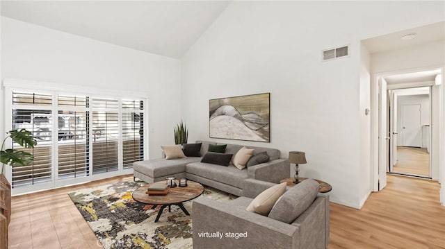 living room with light hardwood / wood-style floors and high vaulted ceiling