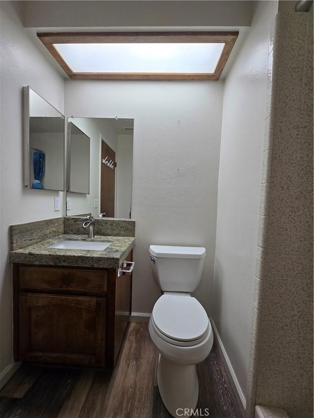 bathroom with toilet, hardwood / wood-style floors, and vanity