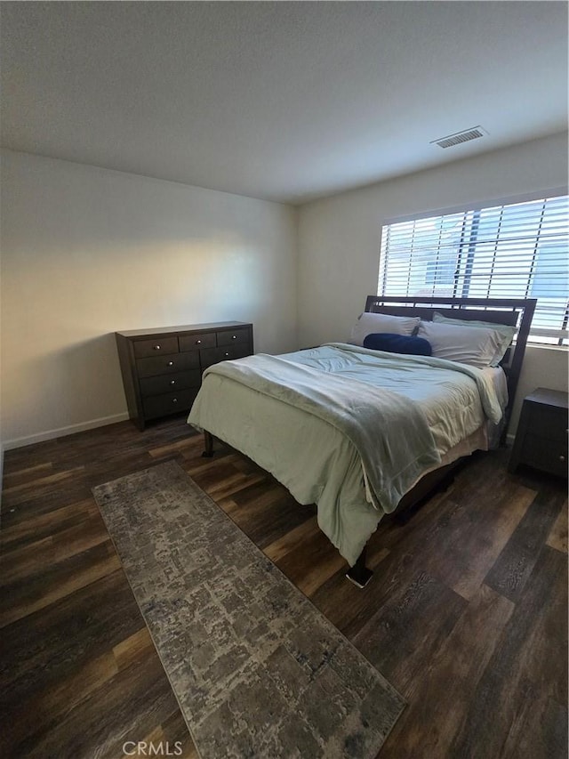 bedroom featuring multiple windows and dark hardwood / wood-style flooring