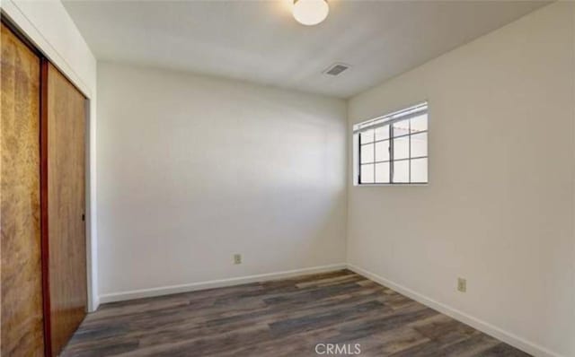 unfurnished bedroom featuring a closet and dark hardwood / wood-style flooring