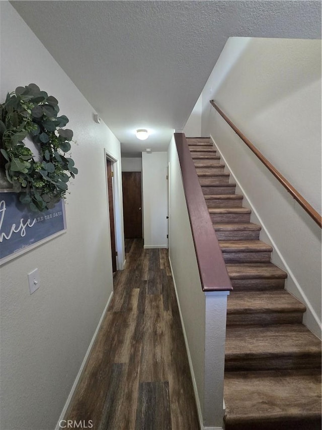 stairway with a textured ceiling and hardwood / wood-style flooring