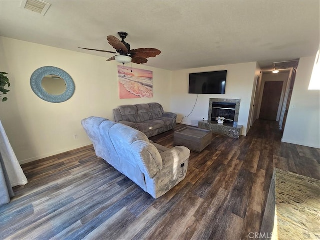 living room with ceiling fan, dark hardwood / wood-style floors, and a tile fireplace