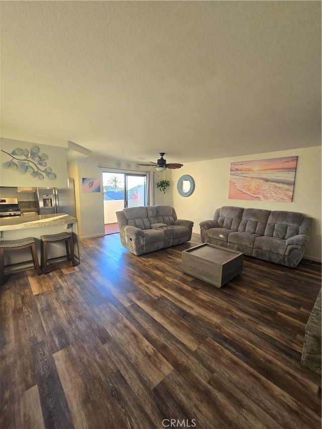 living room featuring ceiling fan, dark hardwood / wood-style floors, and a textured ceiling