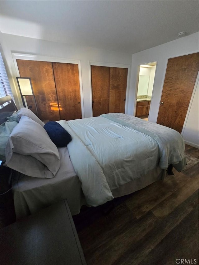 bedroom featuring dark wood-type flooring and multiple closets