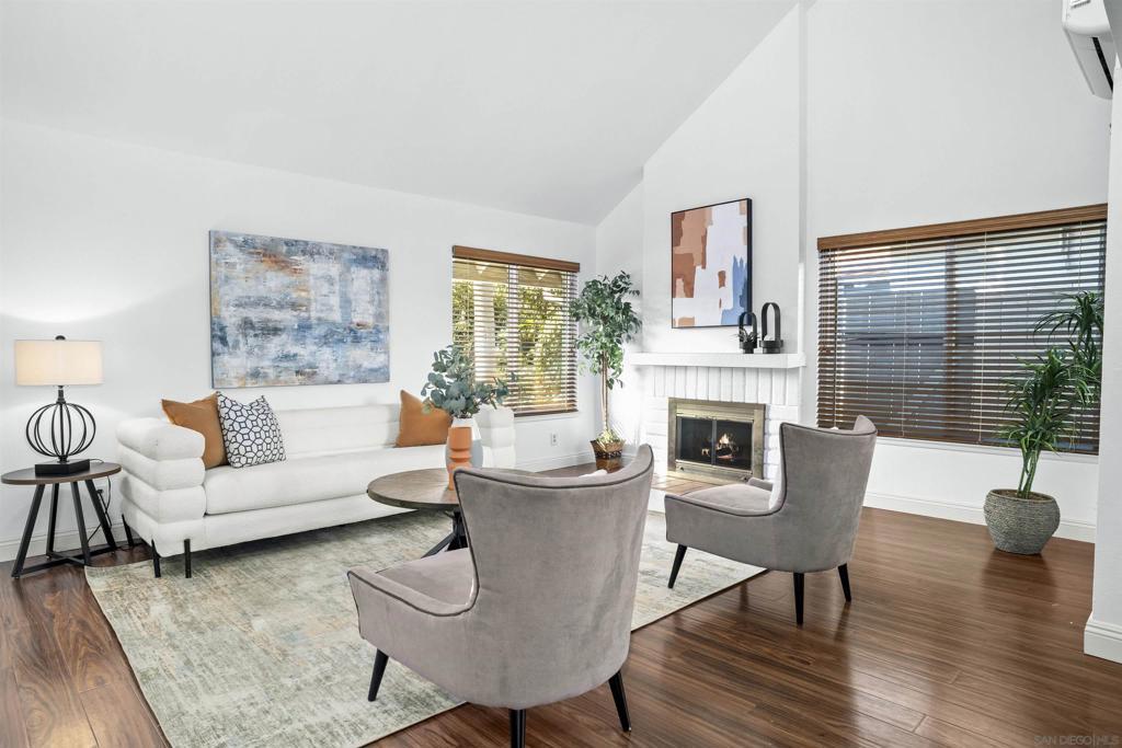 living room with dark hardwood / wood-style flooring, an AC wall unit, a fireplace, and high vaulted ceiling