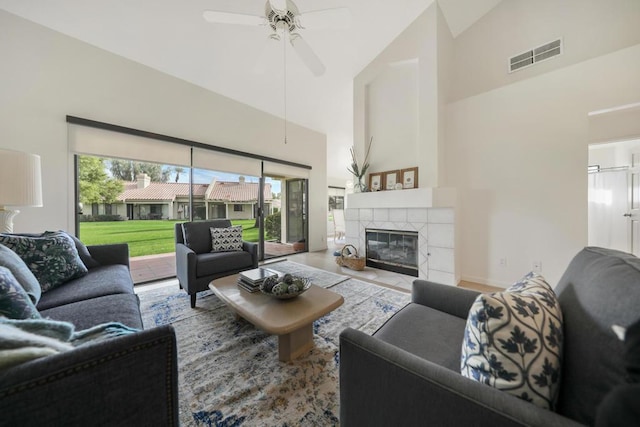 living room featuring hardwood / wood-style flooring, ceiling fan, a fireplace, and high vaulted ceiling