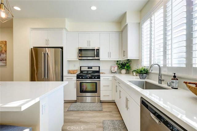 kitchen with white cabinets, pendant lighting, stainless steel appliances, and sink