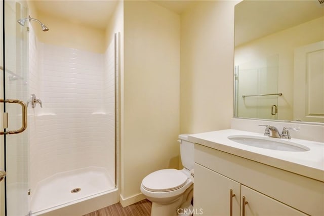 bathroom with vanity, toilet, a shower with shower door, and wood-type flooring