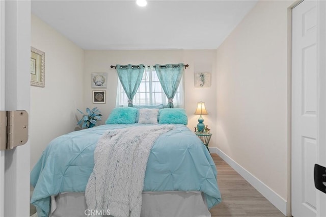 bedroom with light wood-type flooring and baseboards