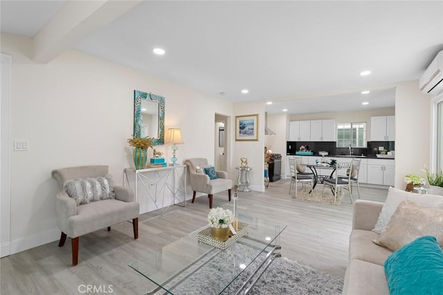 living area featuring light wood finished floors, a wall mounted air conditioner, baseboards, and recessed lighting