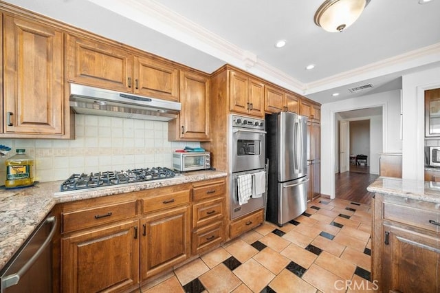 kitchen with light stone countertops, tasteful backsplash, light hardwood / wood-style floors, appliances with stainless steel finishes, and ornamental molding