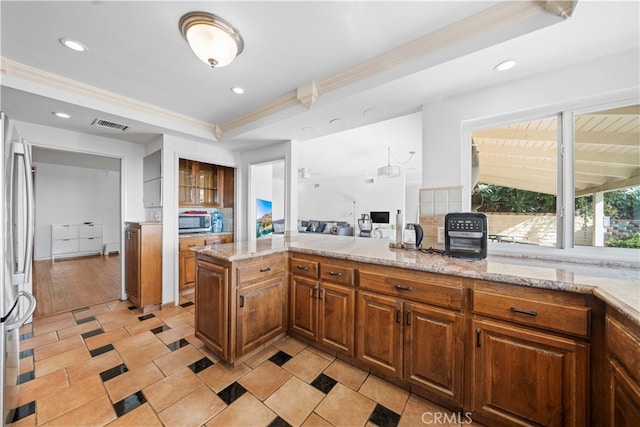 kitchen featuring light stone countertops, stainless steel appliances, crown molding, light hardwood / wood-style floors, and a tray ceiling