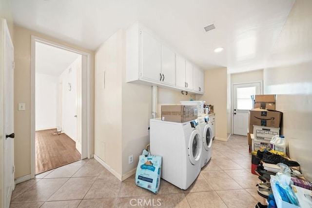 laundry room with cabinets, light hardwood / wood-style floors, and washing machine and clothes dryer