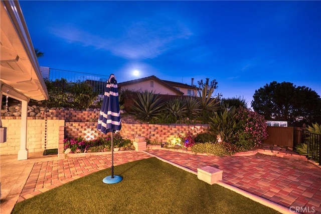 yard at dusk featuring a patio