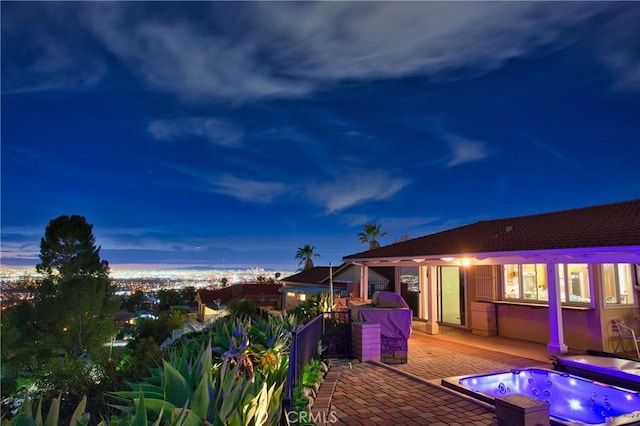 deck at dusk with an outdoor hot tub