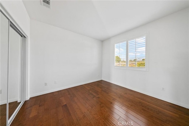 unfurnished bedroom featuring a closet, visible vents, baseboards, and hardwood / wood-style flooring