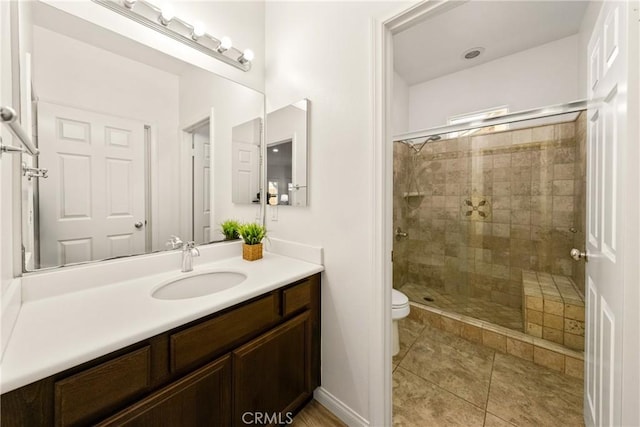 full bathroom featuring toilet, a shower stall, vanity, tile patterned flooring, and baseboards