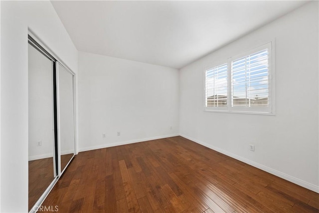 unfurnished bedroom featuring a closet, baseboards, and hardwood / wood-style floors