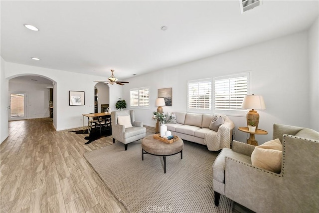 living room with arched walkways, recessed lighting, visible vents, light wood-style flooring, and baseboards