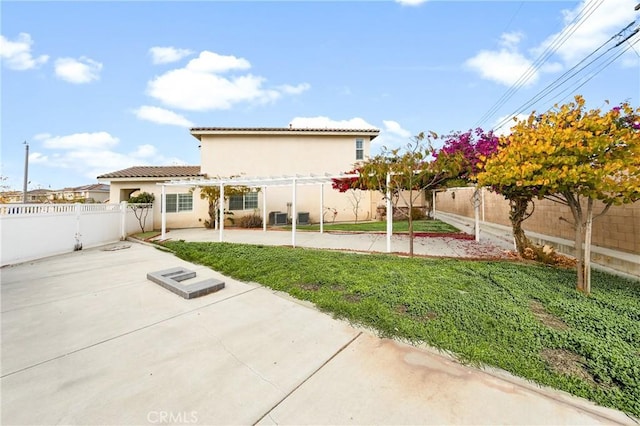 back of property featuring a fenced backyard, a yard, stucco siding, a pergola, and a patio area