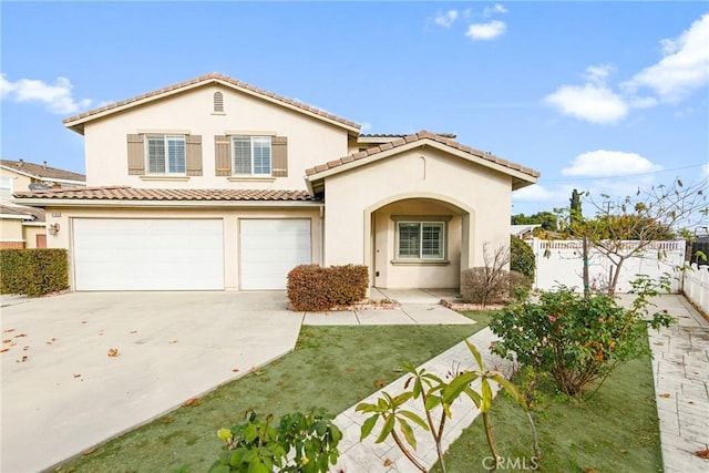 mediterranean / spanish house with concrete driveway, fence, an attached garage, and stucco siding