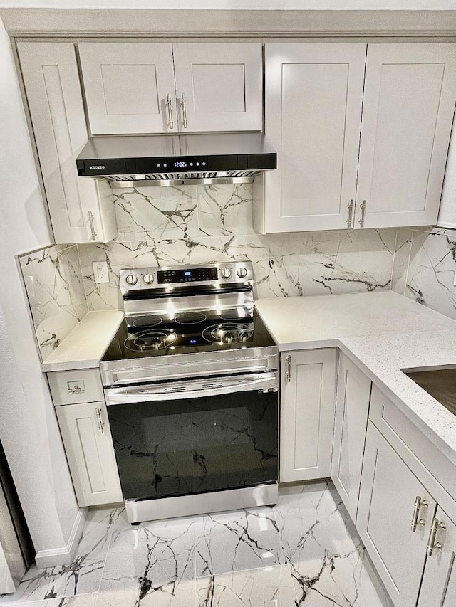 kitchen featuring white cabinets, decorative backsplash, light stone countertops, and stainless steel electric range oven