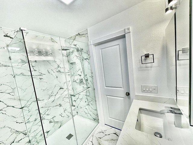 bathroom featuring a textured ceiling, vanity, and tiled shower