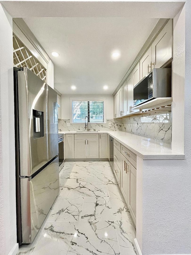 kitchen featuring backsplash, light stone countertops, sink, and appliances with stainless steel finishes