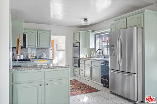 kitchen with appliances with stainless steel finishes, decorative backsplash, sink, kitchen peninsula, and light tile patterned flooring