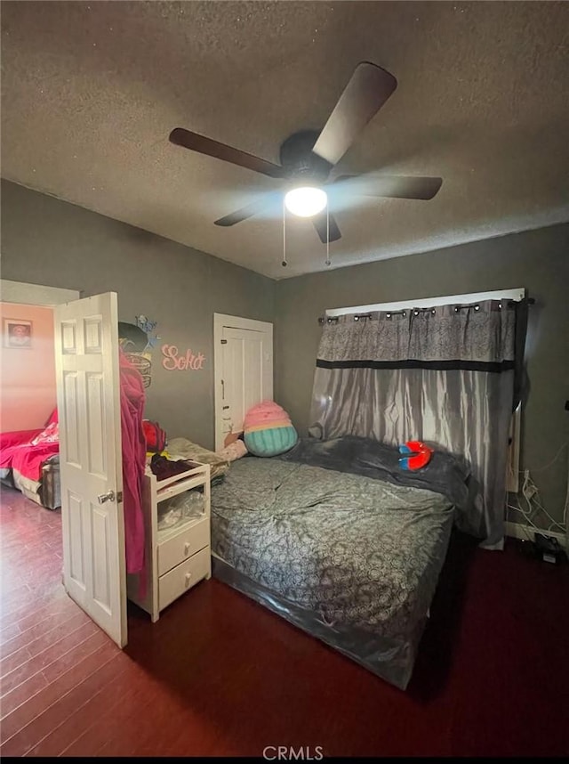 bedroom featuring ceiling fan, dark hardwood / wood-style flooring, and a textured ceiling