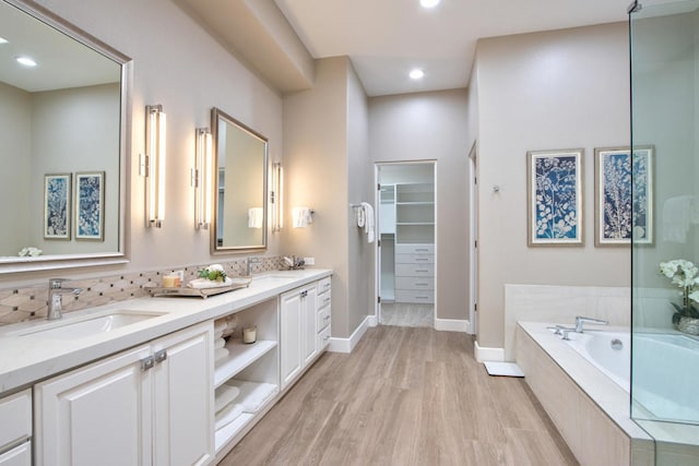 bathroom featuring vanity, a relaxing tiled tub, and hardwood / wood-style flooring