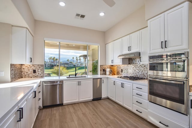 kitchen with appliances with stainless steel finishes, light hardwood / wood-style floors, white cabinetry, and sink