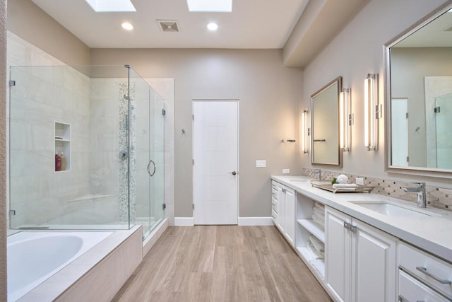 bathroom with vanity, separate shower and tub, wood-type flooring, and a skylight