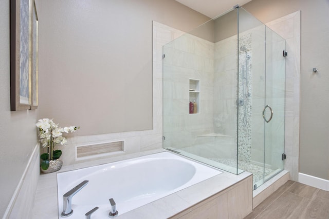 bathroom with wood-type flooring and shower with separate bathtub