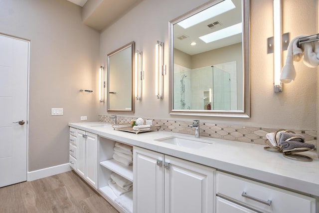 bathroom with hardwood / wood-style floors, vanity, a skylight, and walk in shower