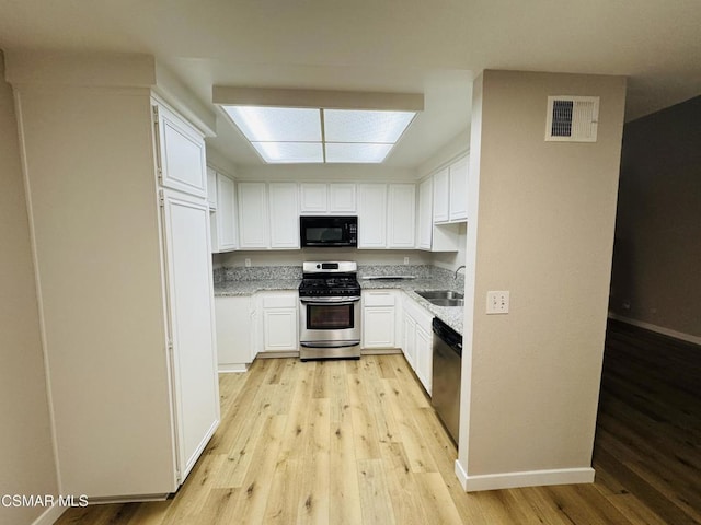 kitchen with sink, white cabinetry, appliances with stainless steel finishes, and light wood-type flooring