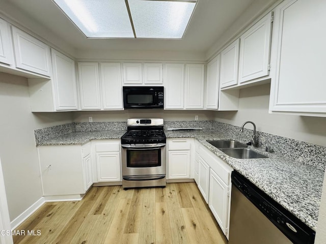 kitchen with white cabinetry, light hardwood / wood-style floors, stainless steel appliances, light stone counters, and sink