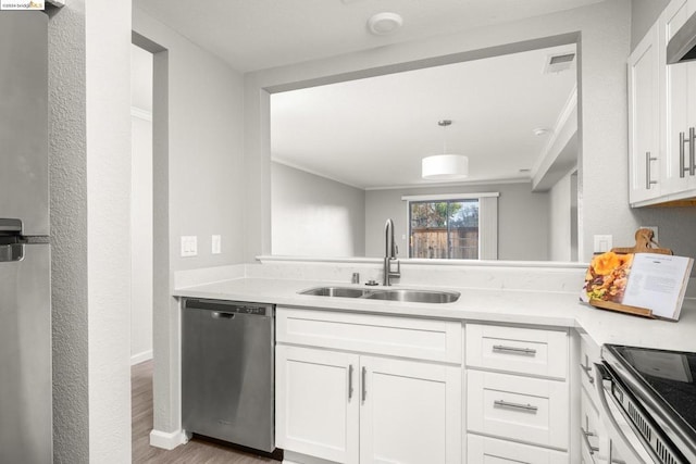 kitchen featuring white cabinets, sink, hanging light fixtures, stainless steel dishwasher, and light hardwood / wood-style floors