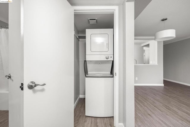 clothes washing area with stacked washer and clothes dryer and hardwood / wood-style floors