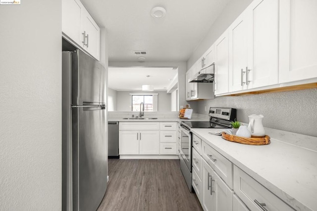 kitchen featuring stainless steel appliances, wood-type flooring, sink, and white cabinets