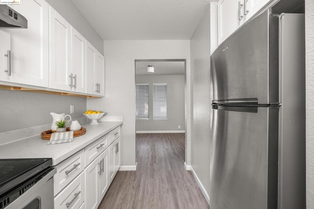 kitchen featuring ventilation hood, appliances with stainless steel finishes, light stone countertops, light hardwood / wood-style floors, and white cabinets