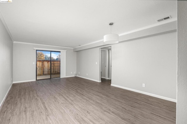 empty room featuring dark wood-type flooring and ornamental molding