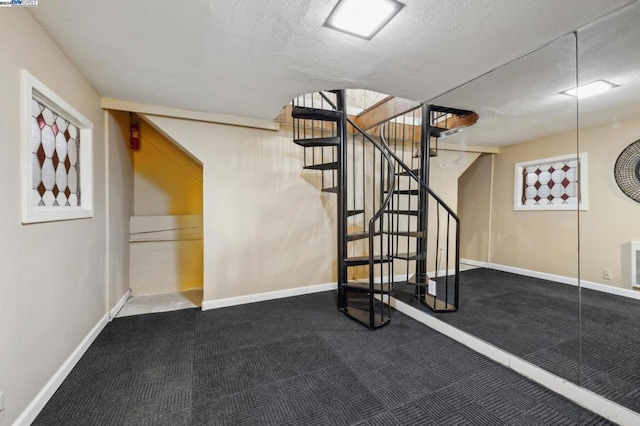 stairway with carpet floors and a textured ceiling