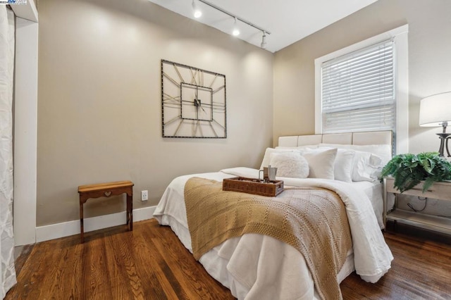 bedroom with dark wood-type flooring and track lighting