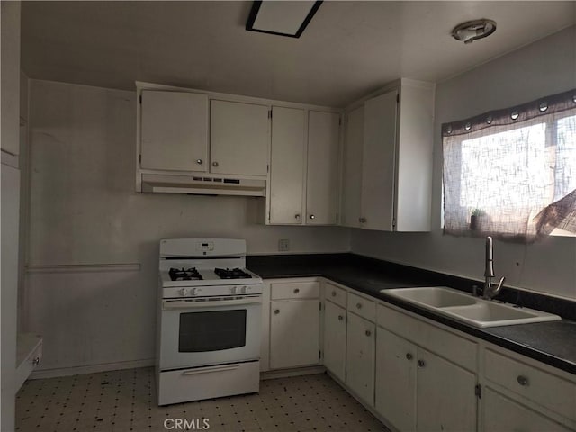 kitchen with white gas range oven, white cabinetry, and sink