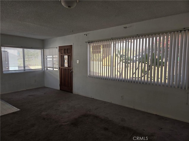 carpeted foyer entrance featuring a textured ceiling