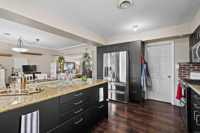 kitchen with light stone counters, dark hardwood / wood-style flooring, stainless steel appliances, and decorative light fixtures