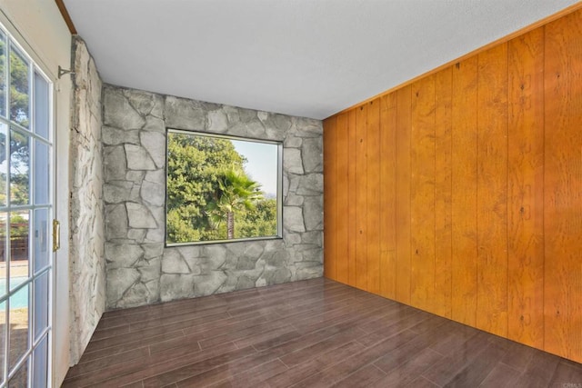 unfurnished room featuring wood walls and dark wood-type flooring