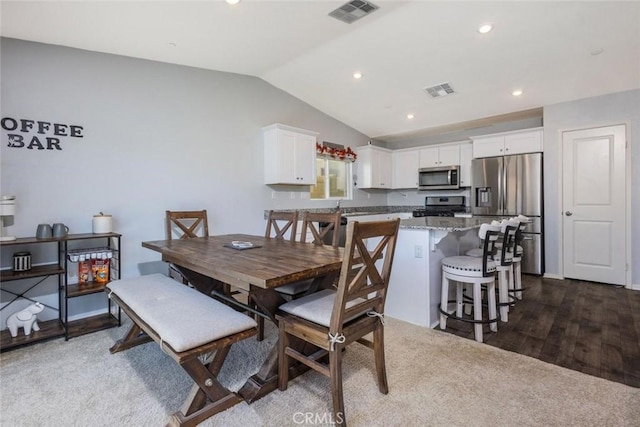 dining area featuring dark wood-type flooring and vaulted ceiling