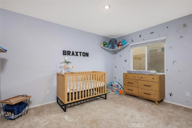 carpeted bedroom featuring a nursery area